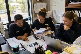 Hospitality staff reviewing documents together in a naturally lit back office, focused on paperwork and checklists, reflecting authentic pre-claim preparation.
